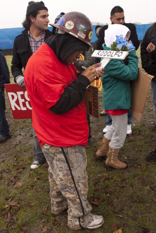 Pablo Arauz. Jose Sifuentes, a worker at the State Farm construction site, signs the cross for deceased worker, Rodolfo Santillan