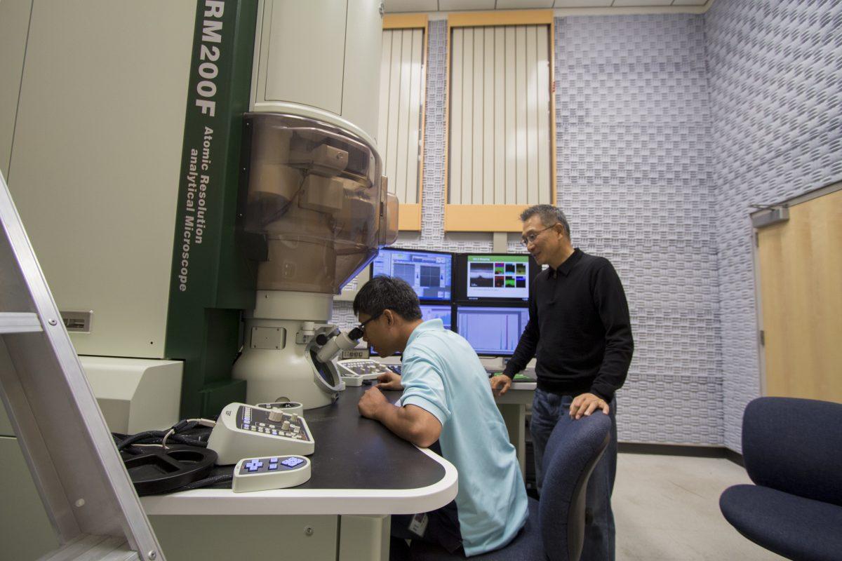 Qiaoxing Wang (left), a material sciences and engineering doctoral student,  looks into an electron microscope in a lab in the Natural Science Engineering Research Laboratory. Wang was a key member of the team working on the transistor project. He worked under the supervision of Moon Kim, a distinguished professor in the same field. Photo by Chris Lin | Mercury Staff.