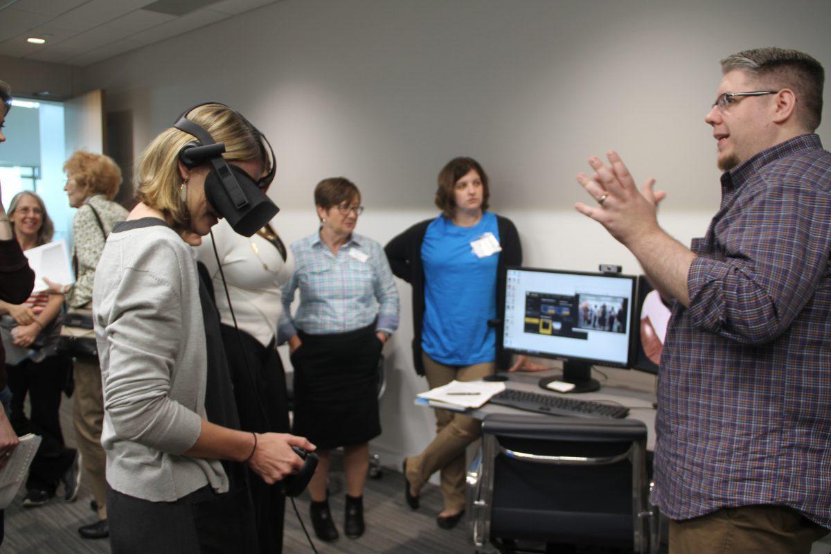 A Brain Performance Institute clinician (right) is showing a member of the public how the Institute uses virtual reality technology to teach their clients social cognitive skills at the grand opening on Oct. 19. Photo by Cindy Folefack | Mercury Staff.