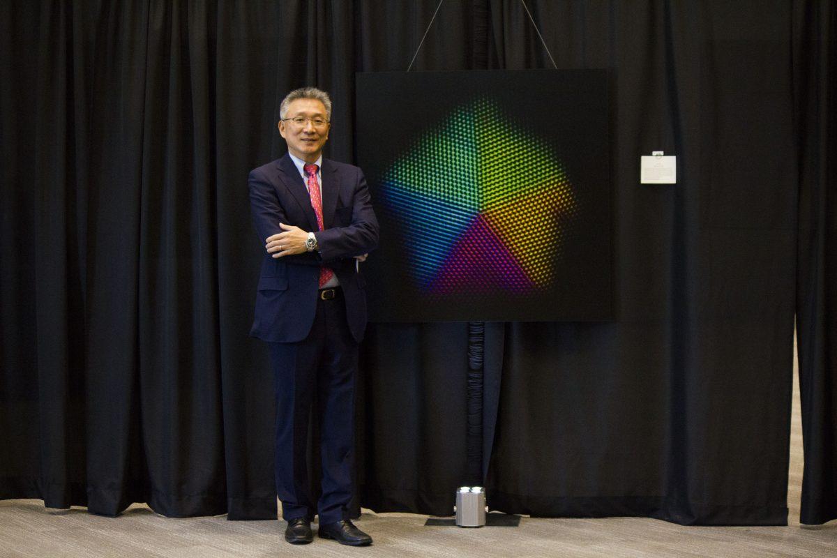 Moon Kim, a material science engineering professor, stands beside a piece of art in his exhibit on Jan. 24 at the Davidson-Gundy Alumni Center. The exhibition featured art composed of nanolevel imagery. Photo by Michael Stout | Mercury Staff.