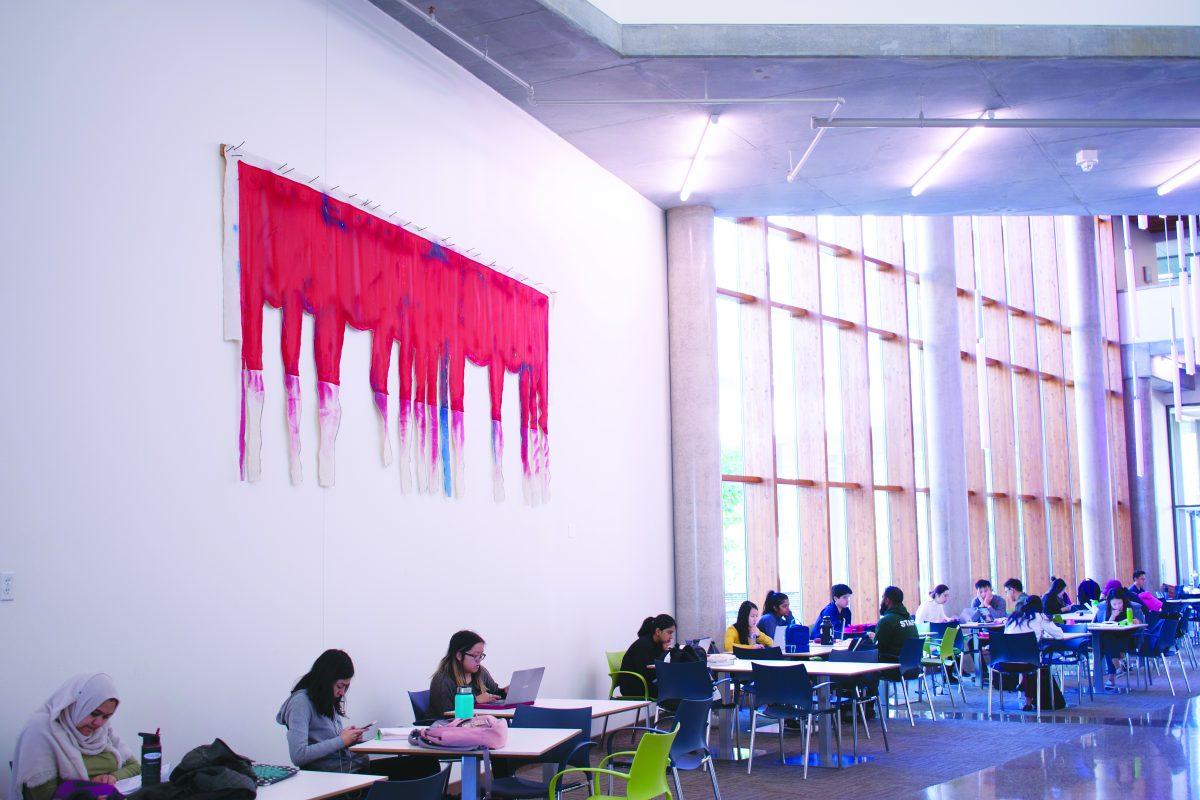 “Joni's Chorus Line,” part of the Davidow art collection, hangs in the atrium of JSOM II across from the undergraduate trading lab. Photo by Nadine Omeis | Mercury Staff.